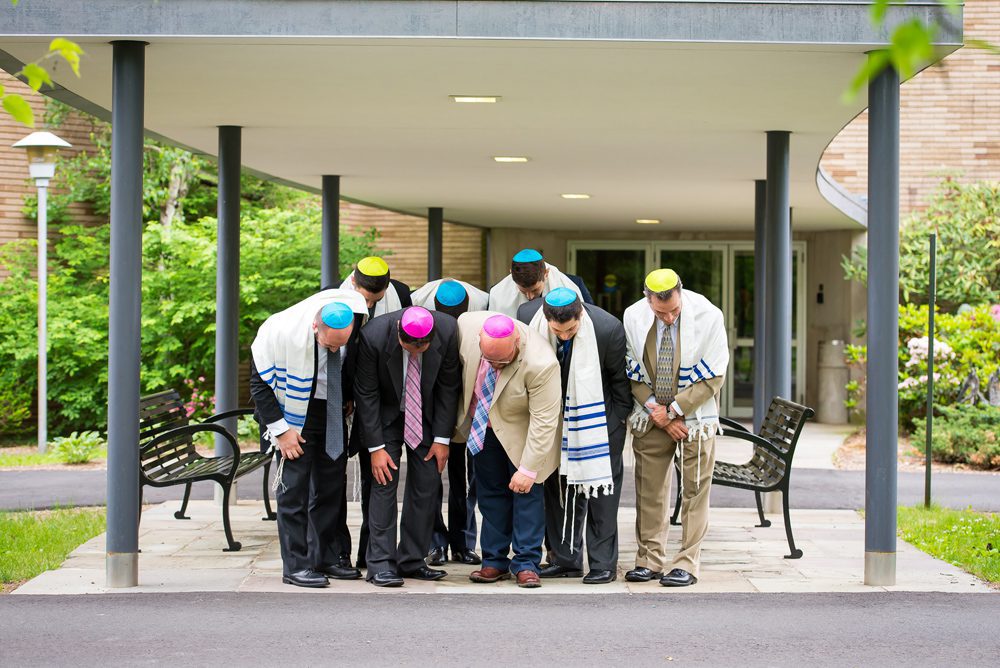A group of men bow their heads to show their colorful yarmulkes