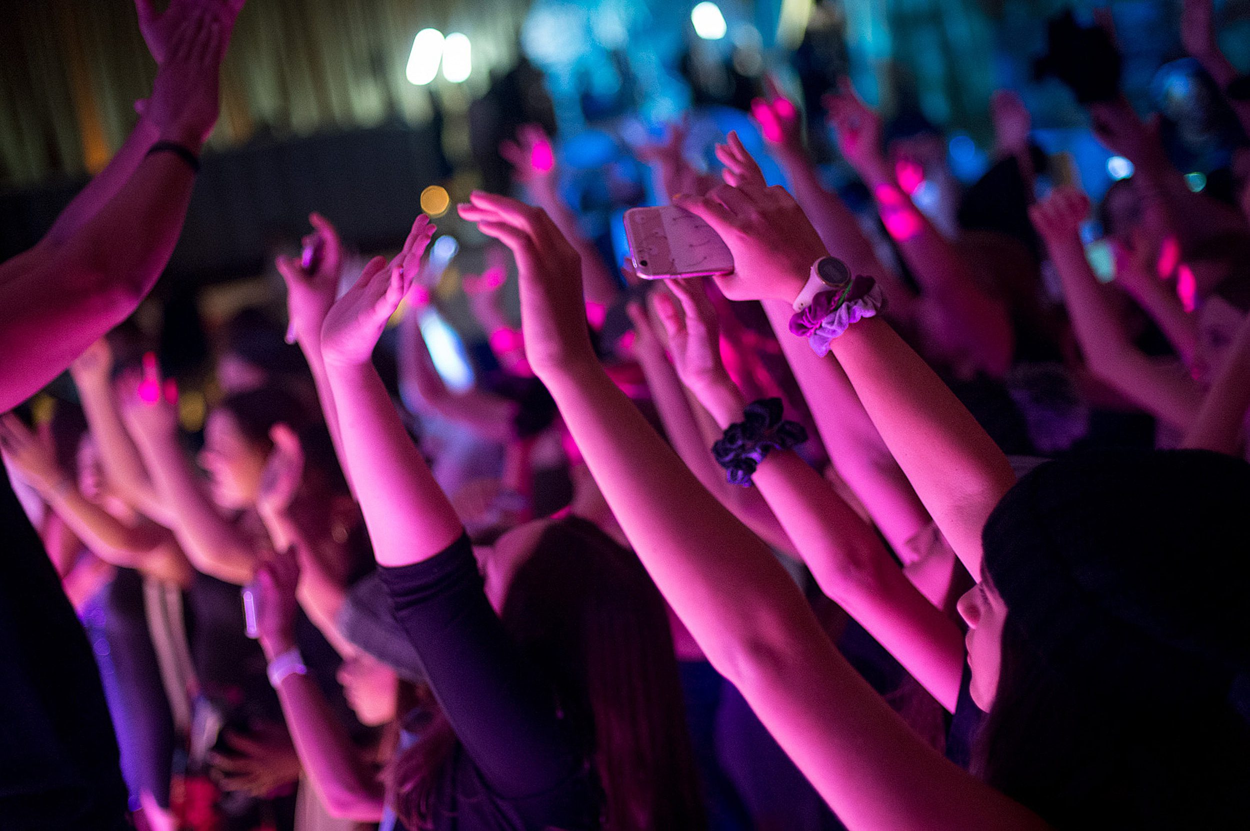 Teenagers raise their hands and phones while dancing at a Bar or Bat Mitzvah