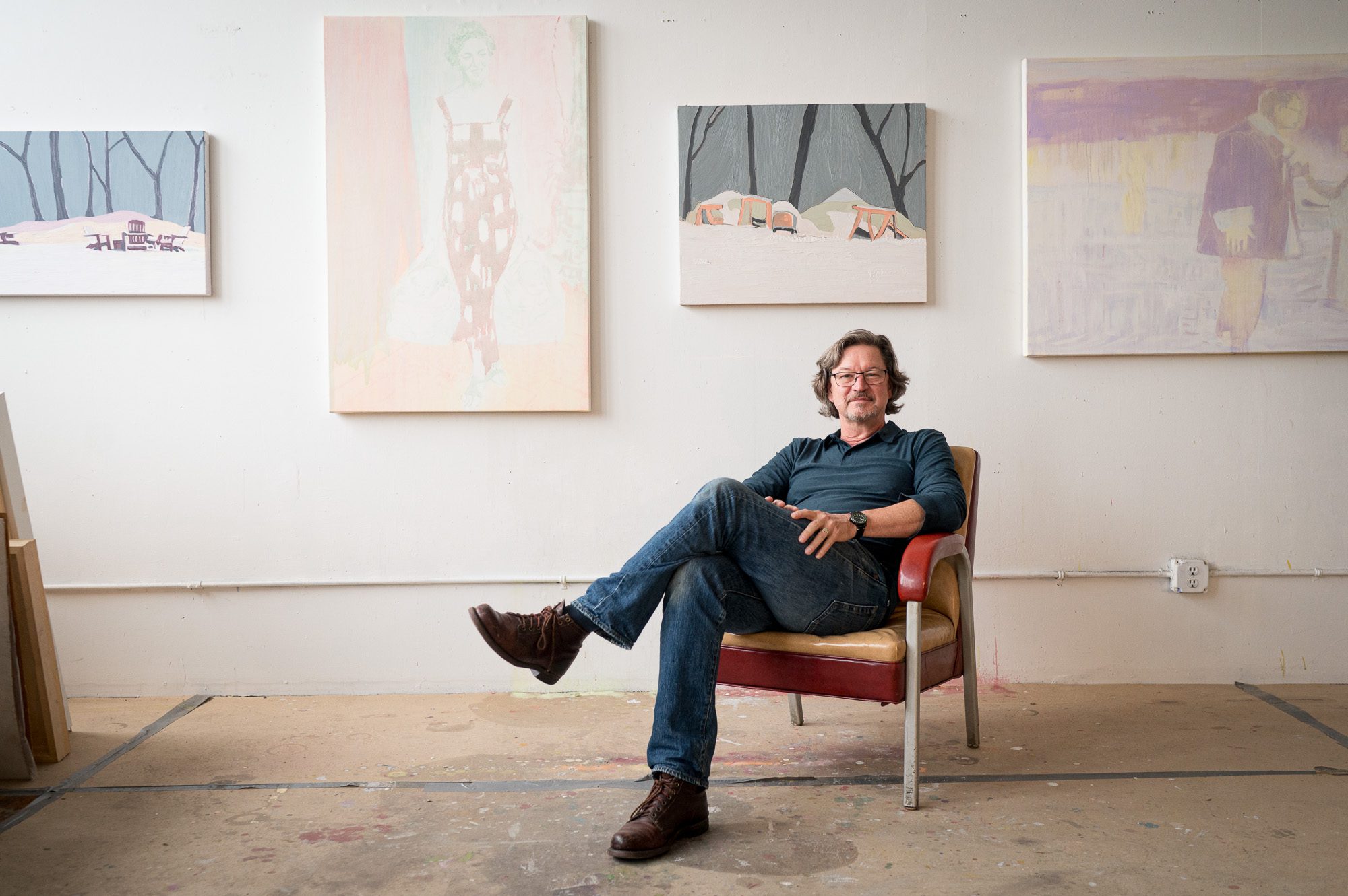 Artist sitting in chair in front of his work