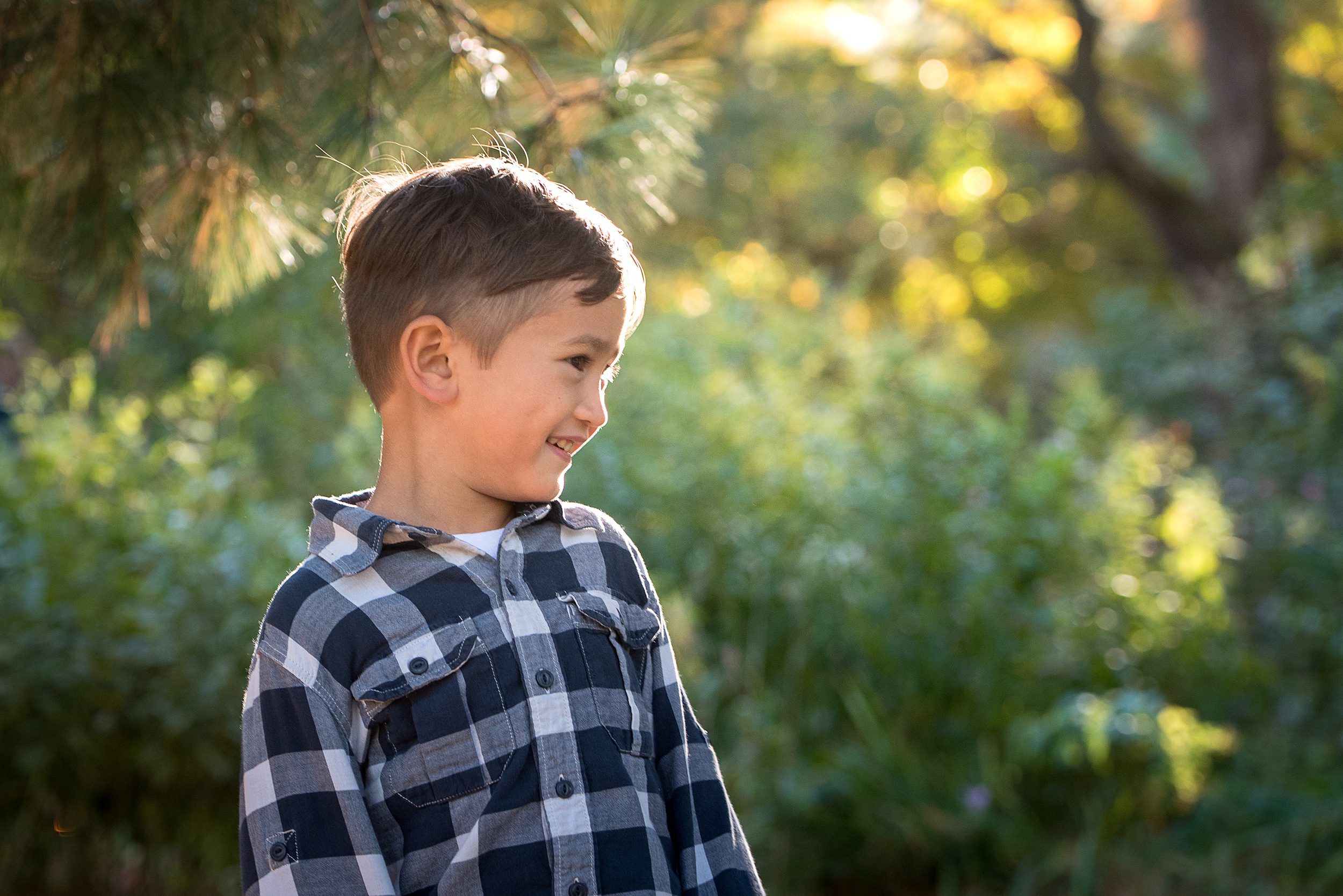 A young boy plays in a park in a blue plaid button down shirt at sunset after his day at a daycare in Madison CT