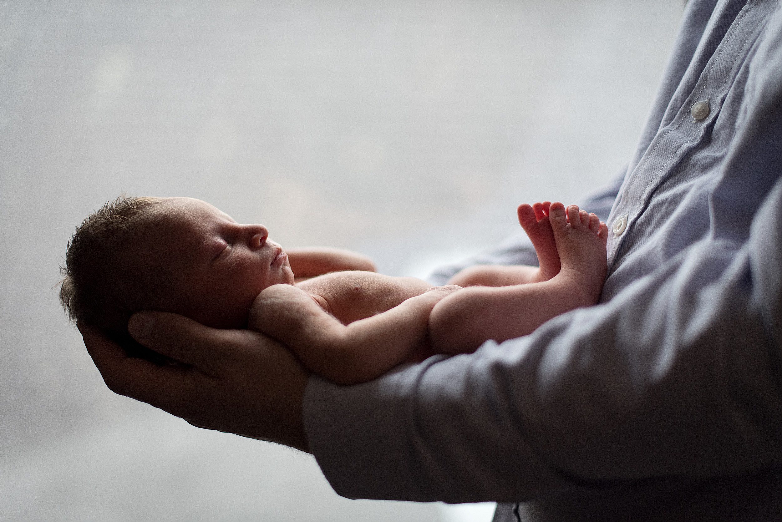 A newborn baby sleeps in dad's arms thanks to yale maternal fetal medicine