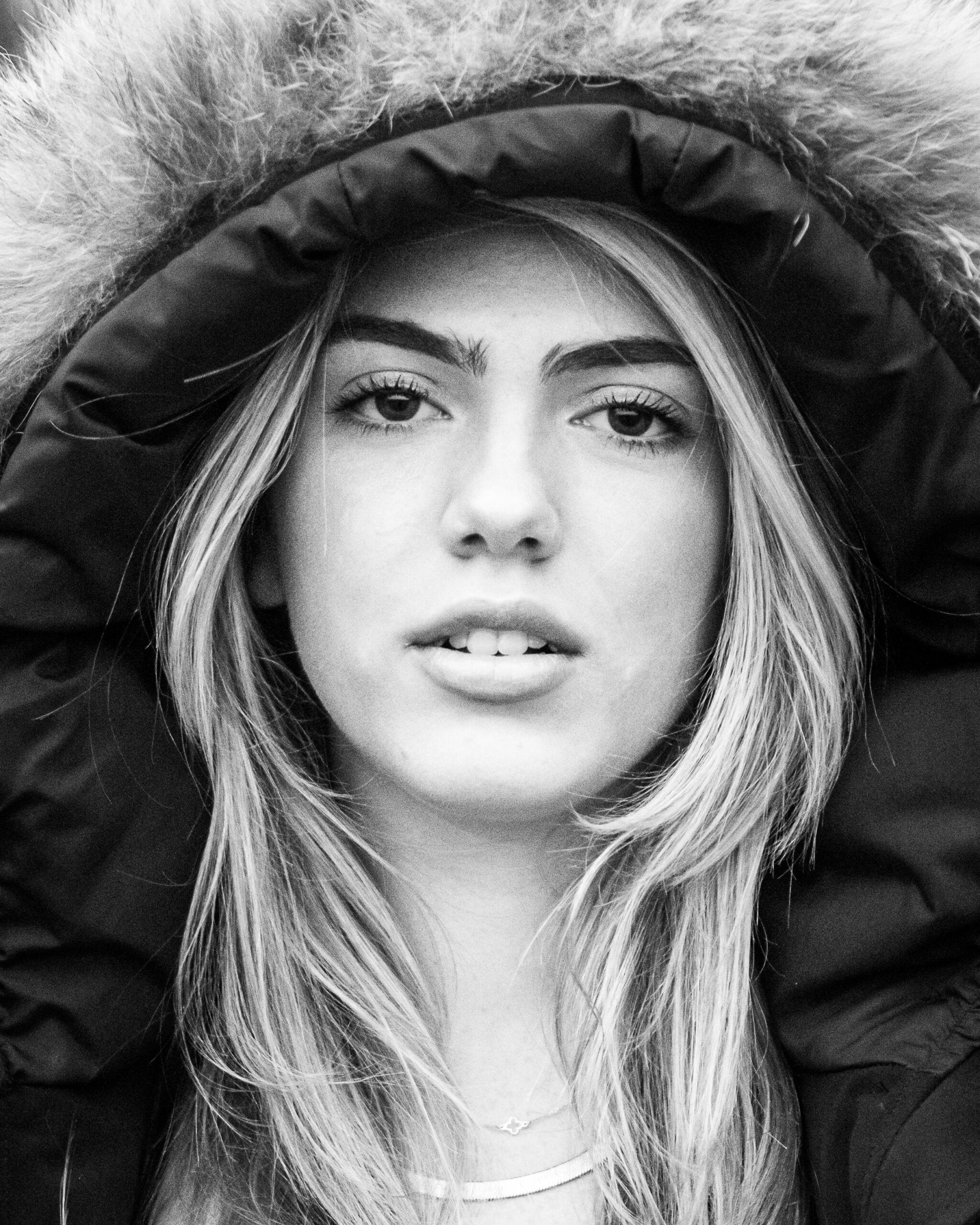 A black and white closeup of a woman in a large parka after visiting boutiques in guilford ct