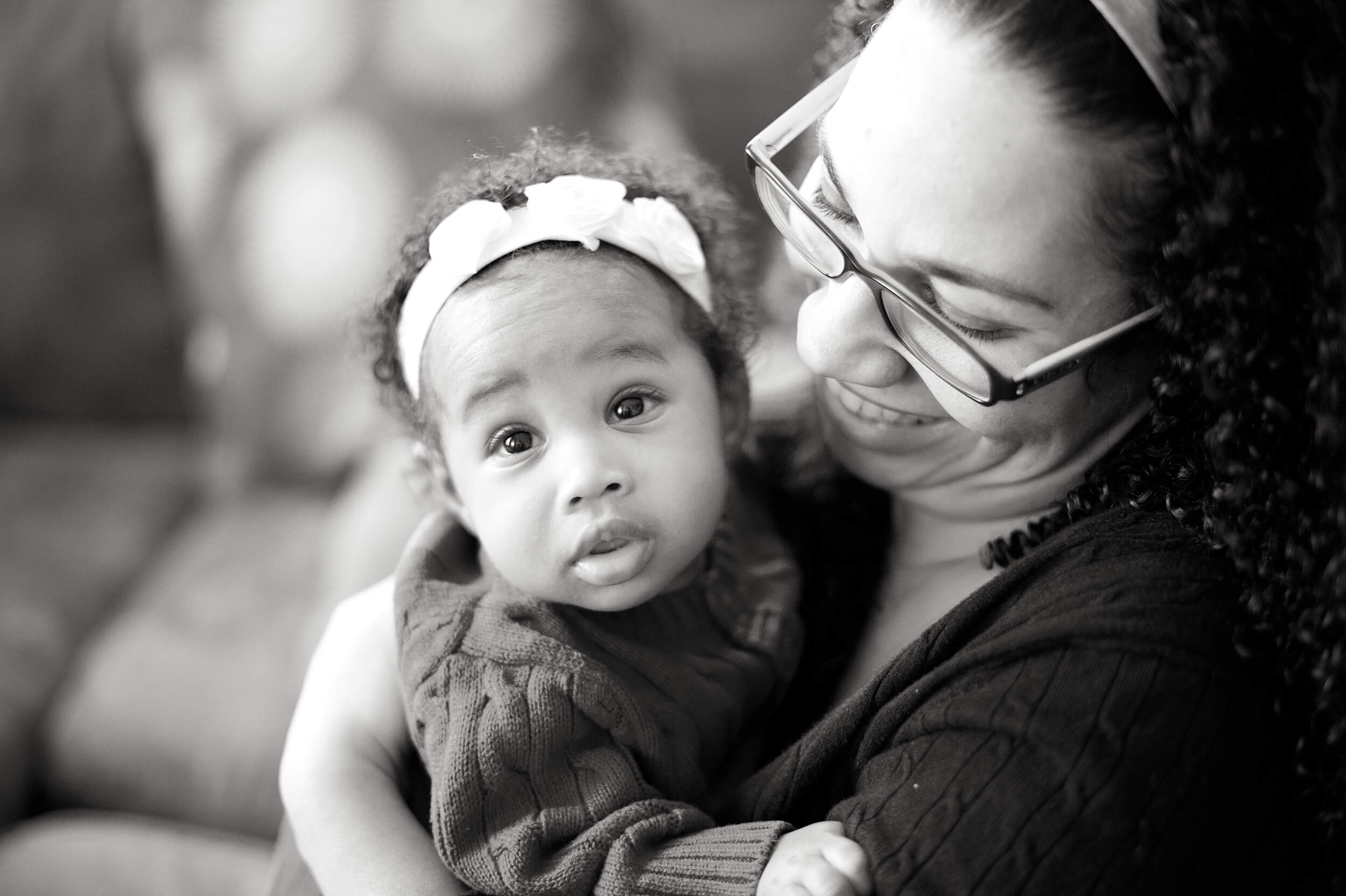 A look down at a happy mom hugging her infant daughter in matching sweaters in black and white after some kids yoga in connecticut