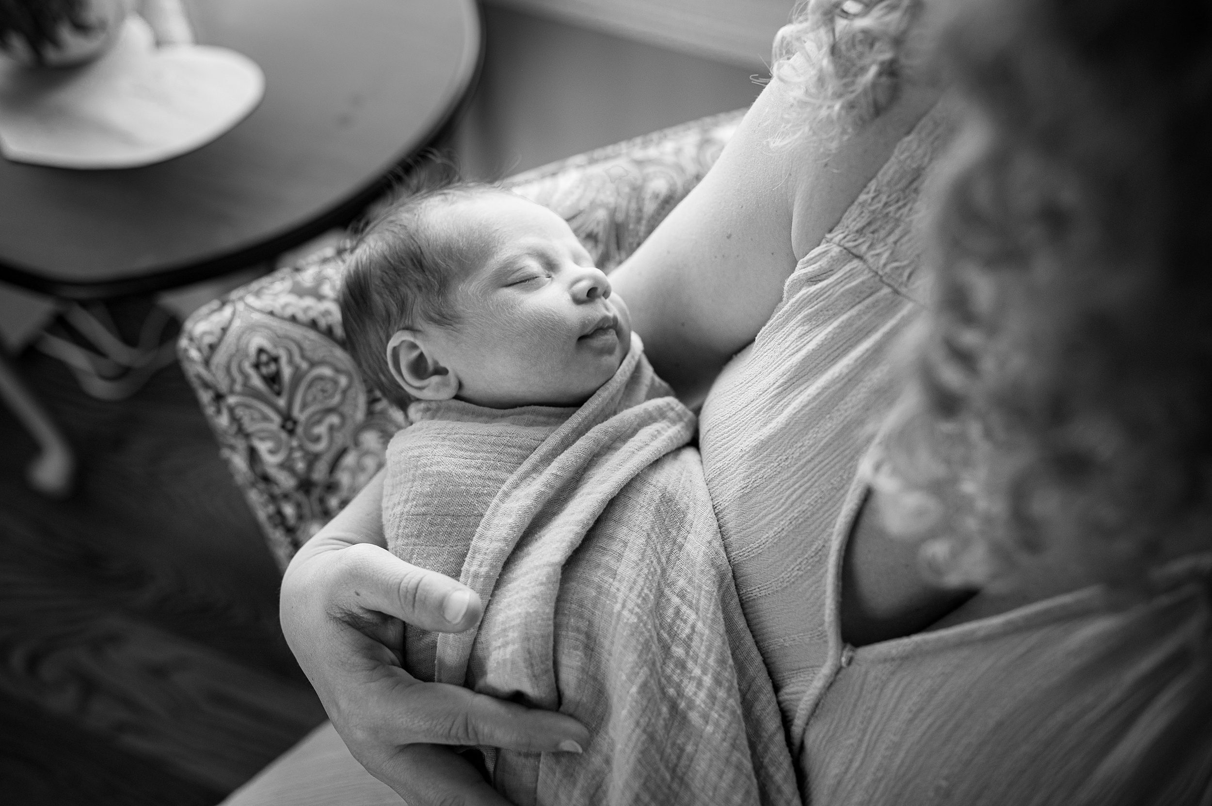 A look down to a sleeping newborn baby in mom's arms on a chair before finding playgrounds in new haven ct